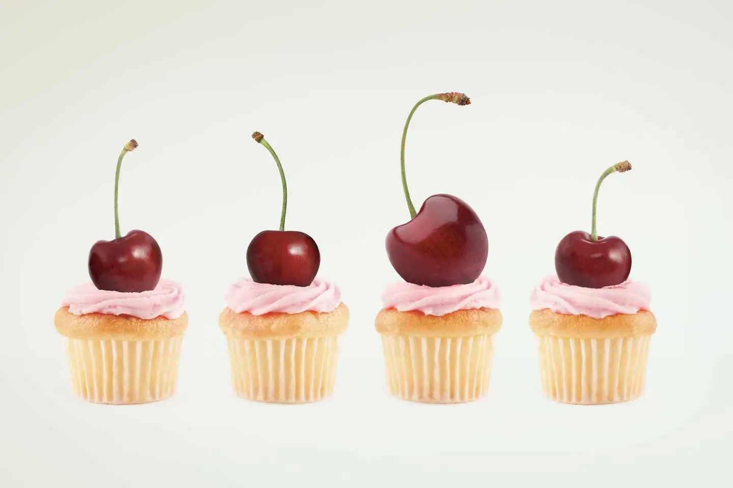 Four small cakes topped with cherries